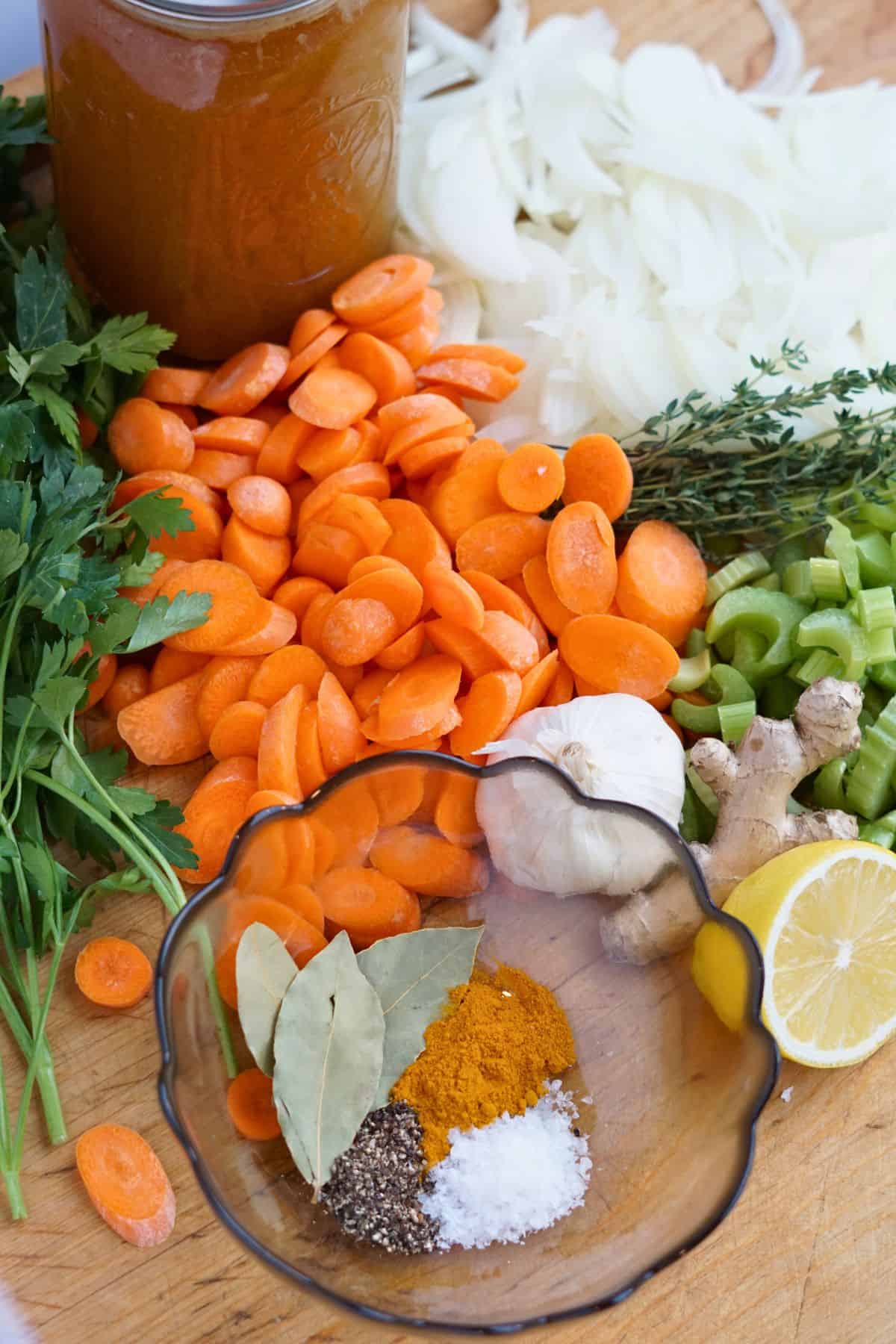 spices and cut up vegetables on cutting board next to jar of bone broth