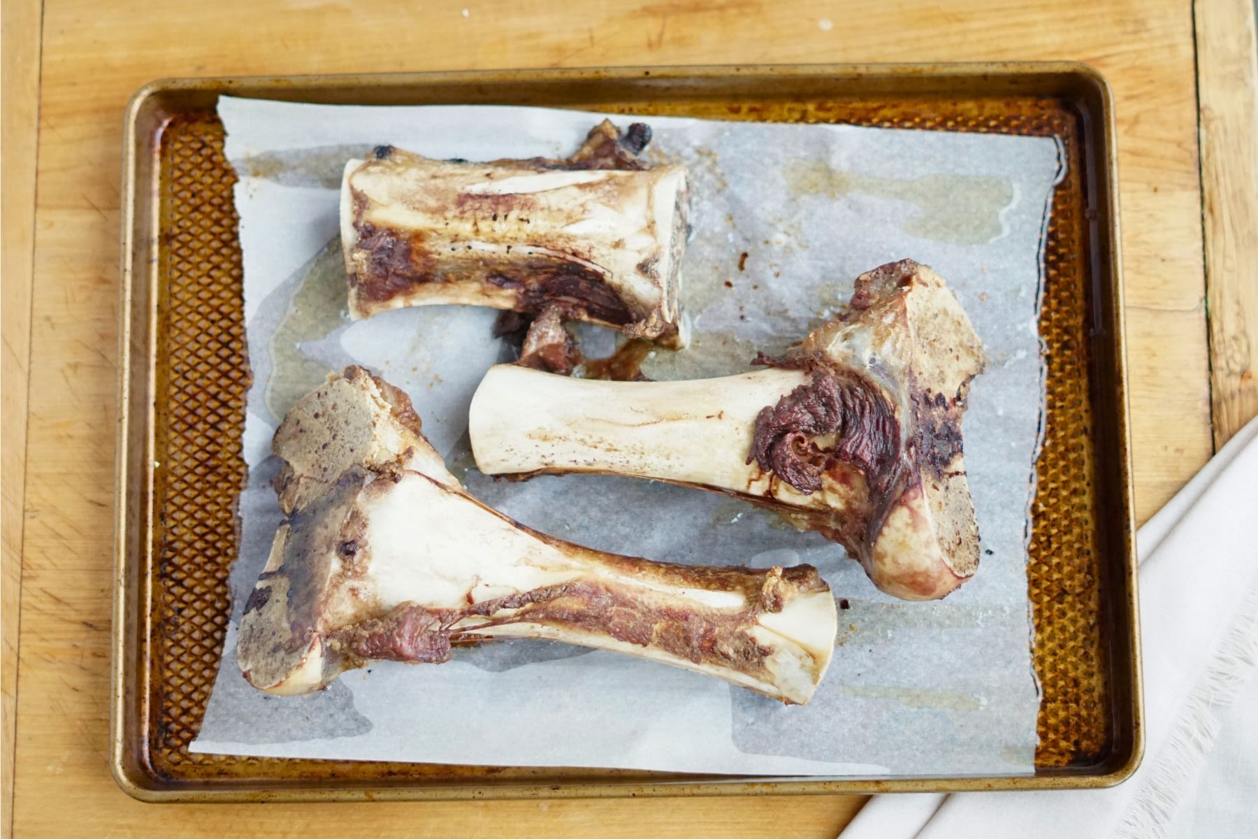 three roasted beef bones on a sheet pan