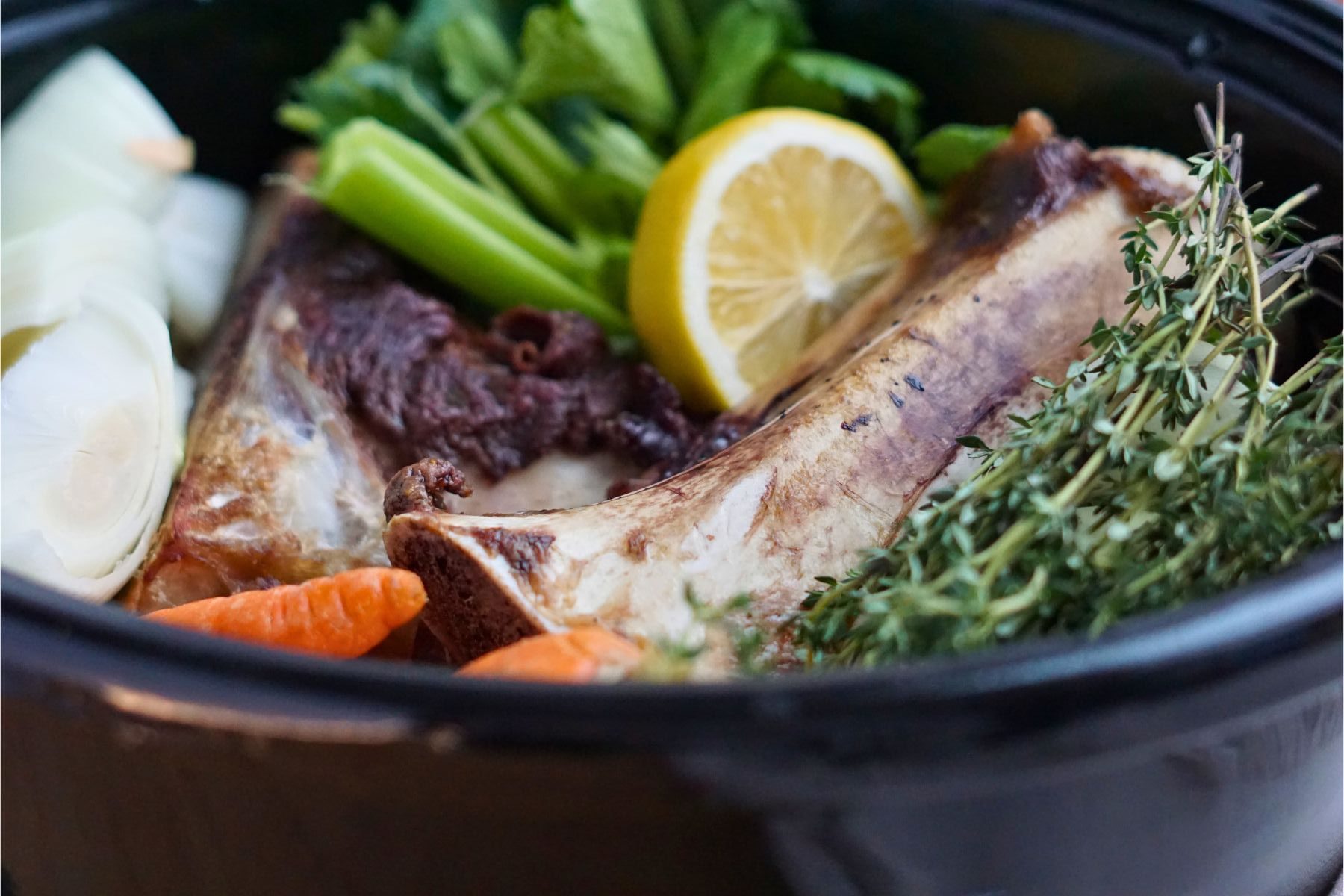 close up of roasted beef bones in crock pot with vegetables
