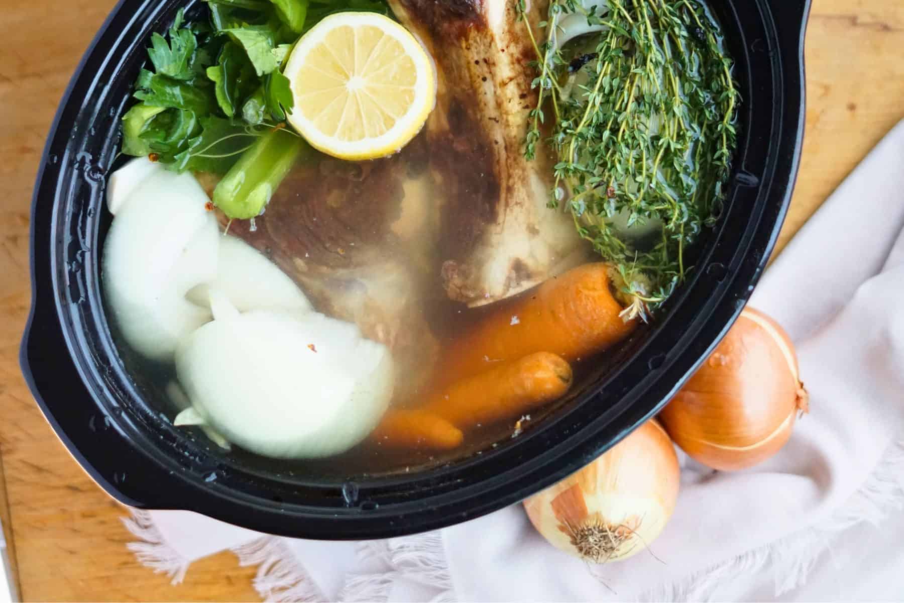 bones and vegetables floating in water in crock pot