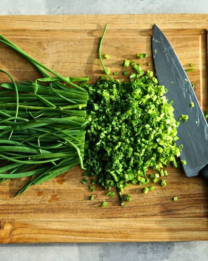 finely diced chives next to a knife on a cutting board