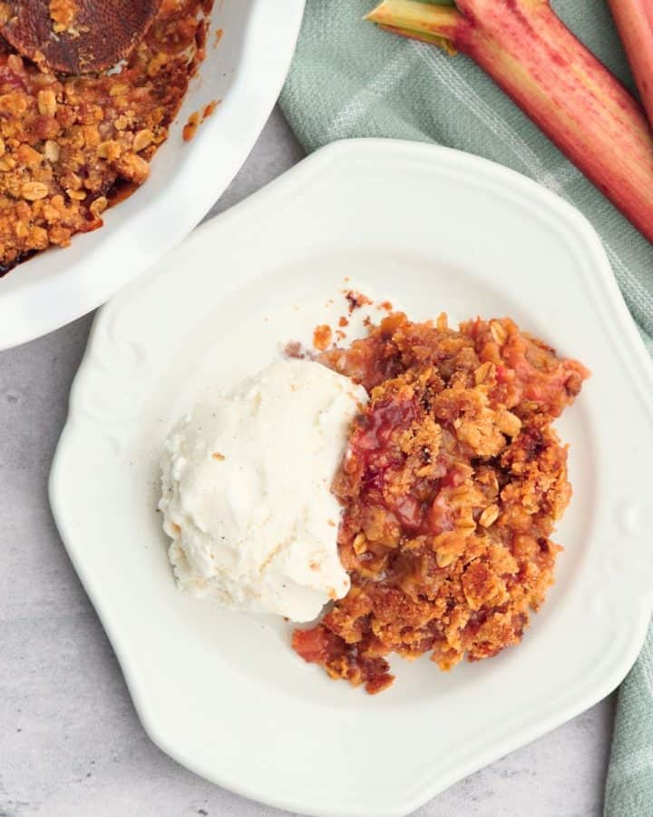 rhubarb crisp on white plate with scoop of vanilla ice cream