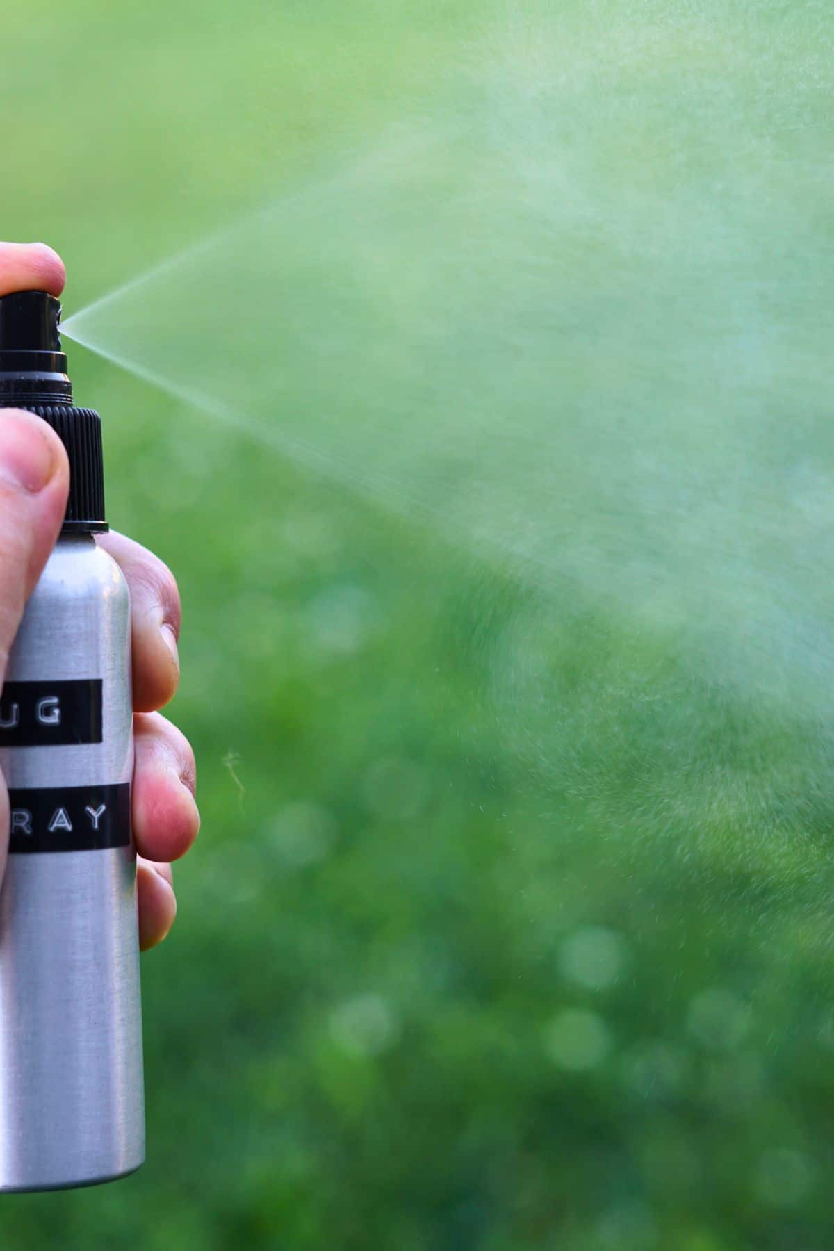 hand spraying bottle of bug spray into the air