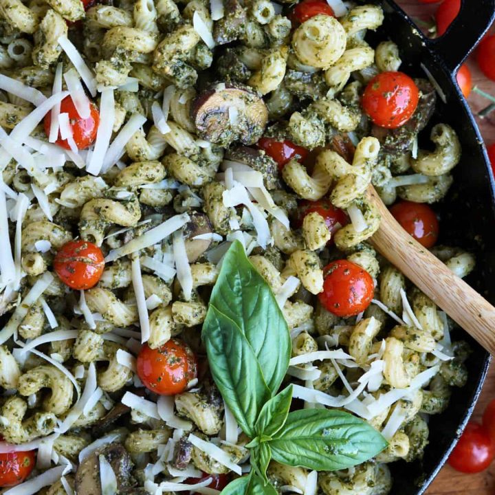 finished pesto cavatappi in cast iron pan with sprig of basil