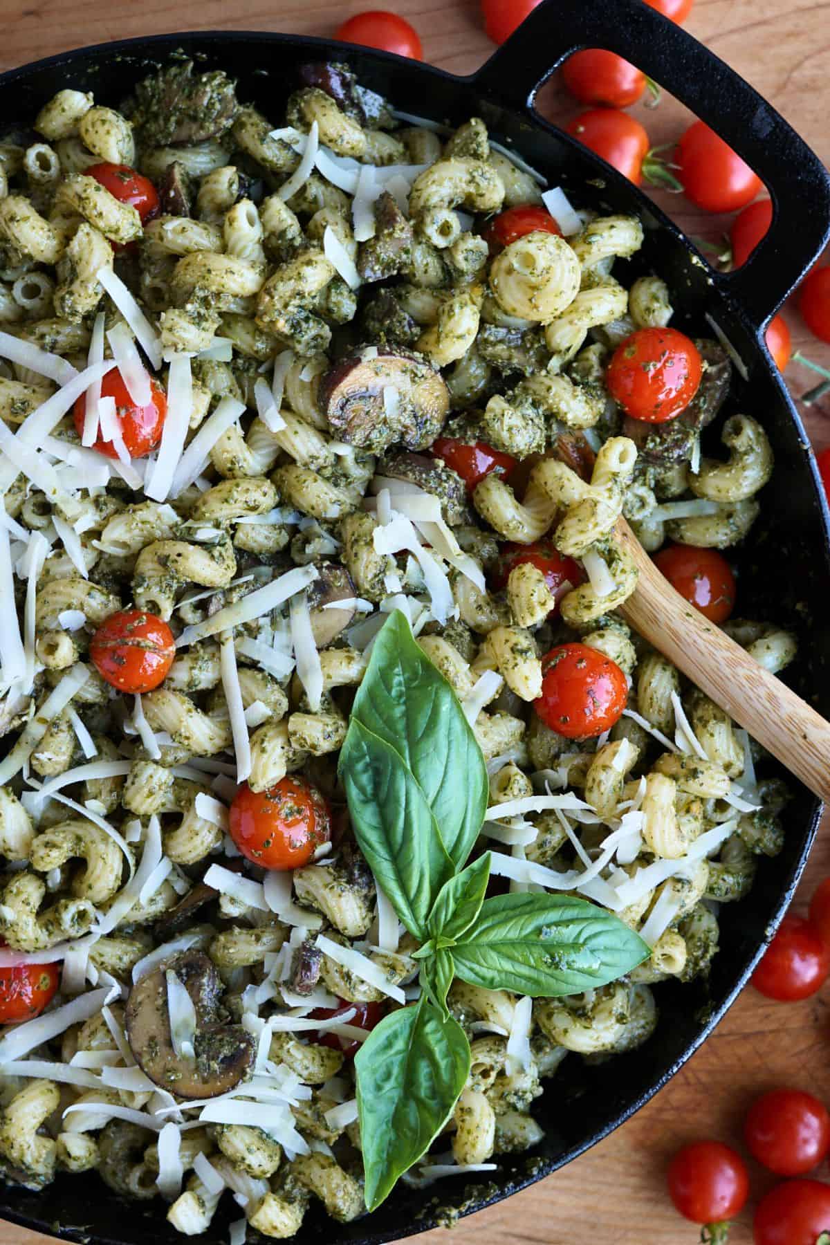 finished pesto cavatappi in cast iron pan with sprig of basil