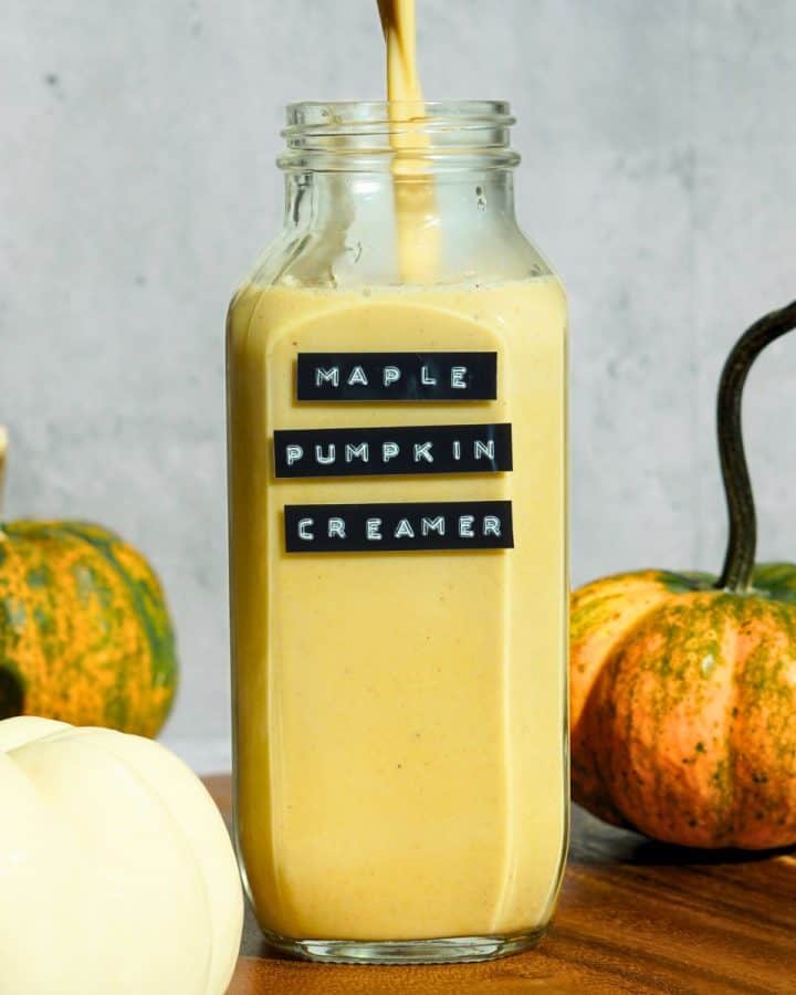 maple pumpkin spice coffee creamer pouring into glass jar with black label on front