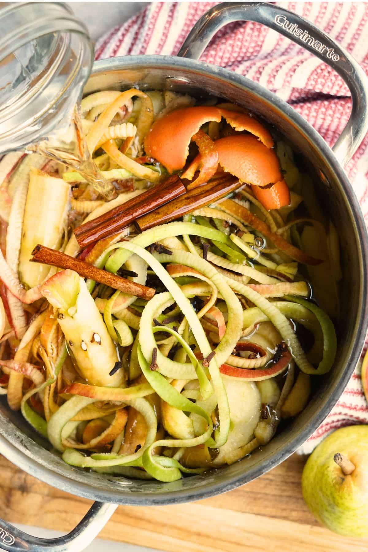 water pouring into large pot of apple and pear scraps and cinnamon sticks