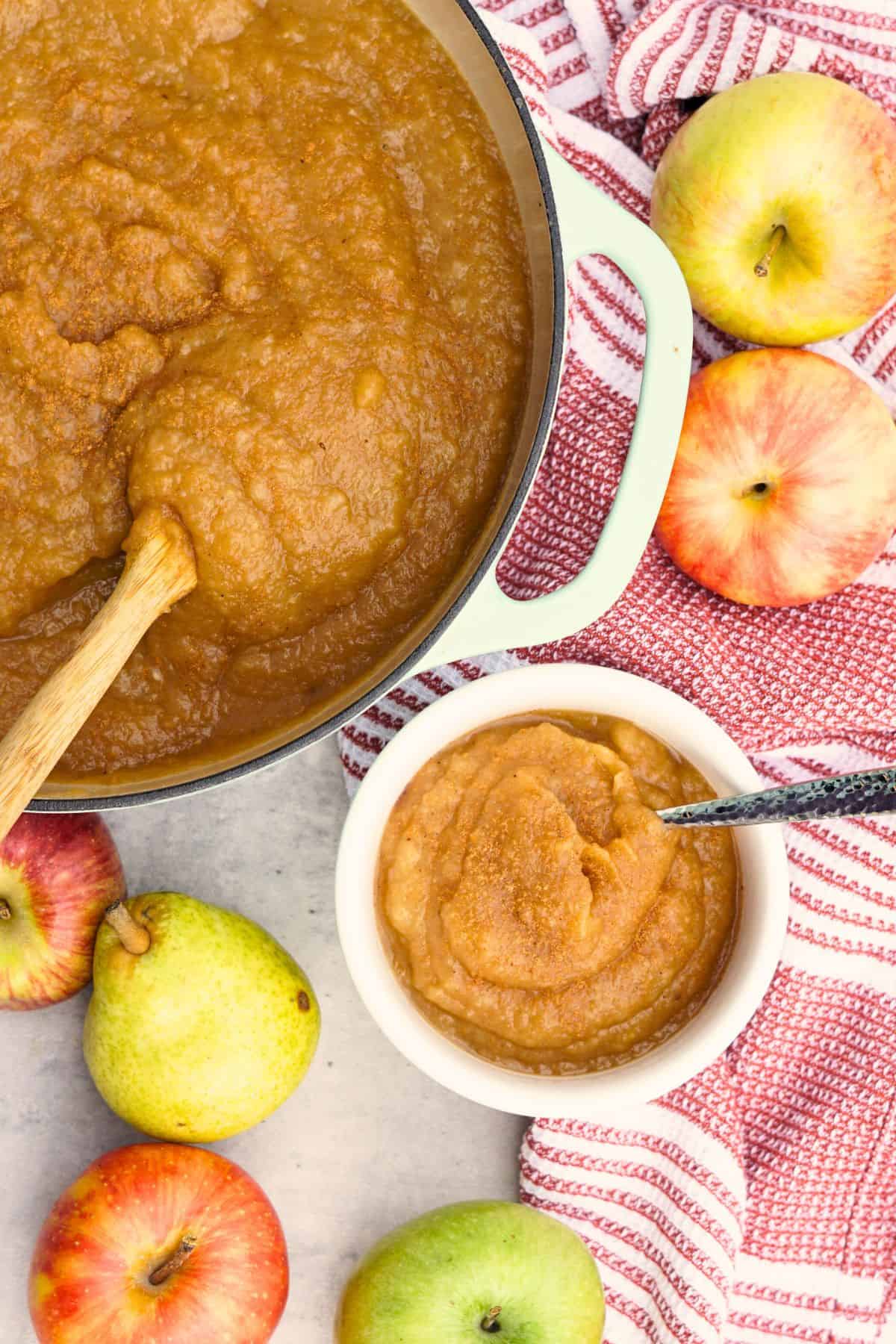 bowl of pear applesauce next to a large pot of pear applesauce