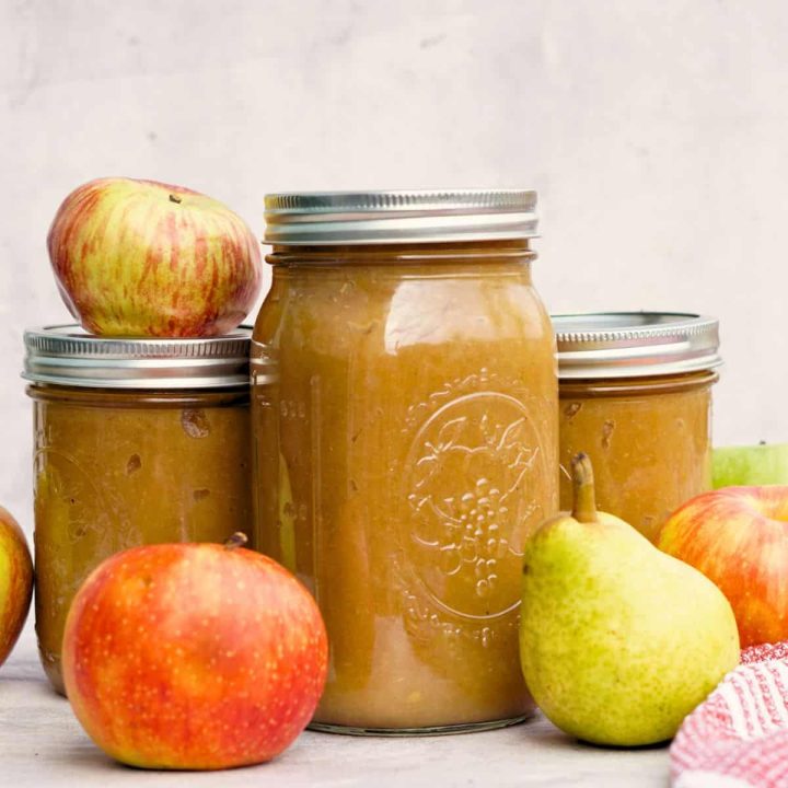 3 jars of spiced pear applesauce on counter next to whole apples and pears