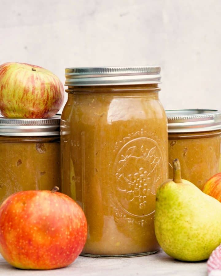 3 jars of spiced pear applesauce on counter next to whole apples and pears