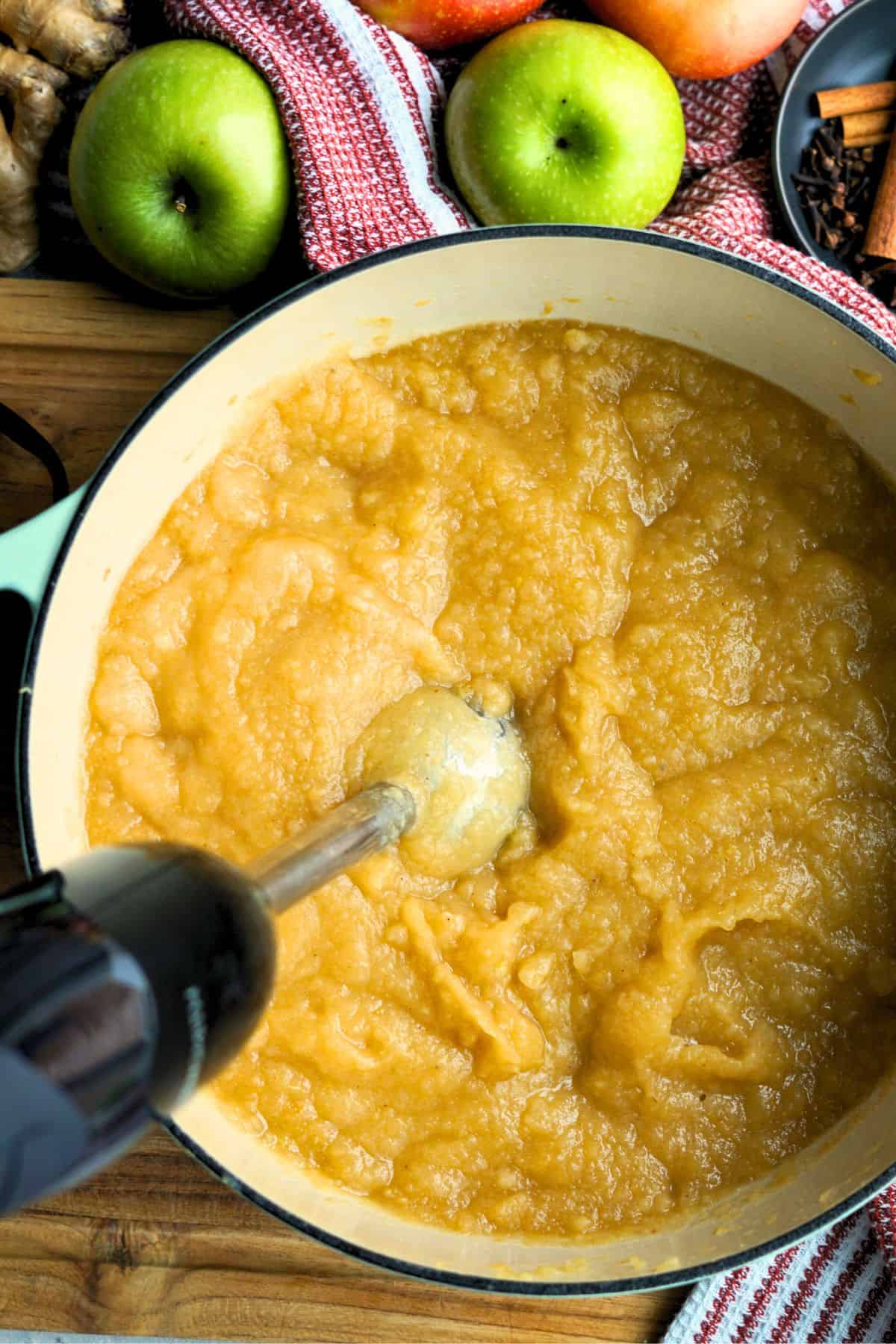 immersion blender pureeing apples and pears into pear applesauce in a large pot
