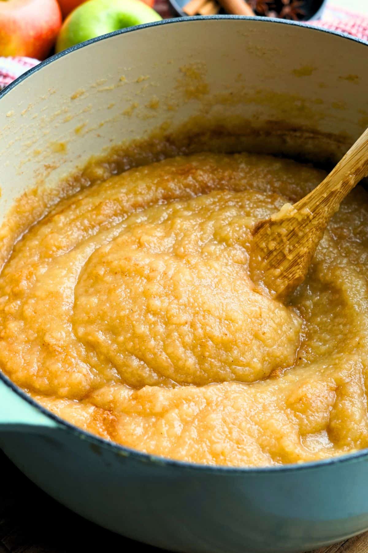wooden spoon stirring pear applesauce in a large pot